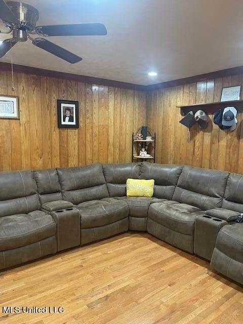 living room with light hardwood / wood-style flooring, ceiling fan, and wood walls