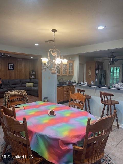 tiled dining space with ceiling fan with notable chandelier