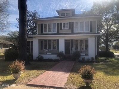 view of property with a porch and a front lawn