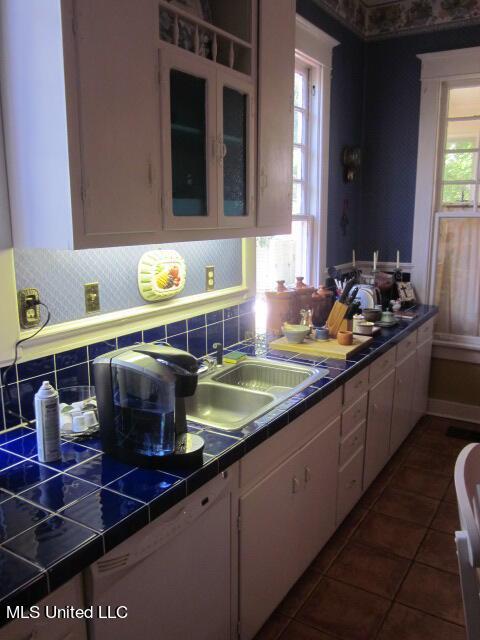 400 Crockett Ave, Greenwood, MS 38930 - kitchen featuring sink, backsplash, dark tile patterned floors, and white cabinets