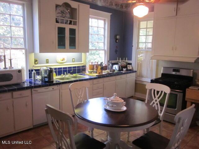 400 Crockett Ave, Greenwood, MS 38930 - kitchen with white cabinetry, stainless steel range with gas stovetop, white dishwasher, and tile counters