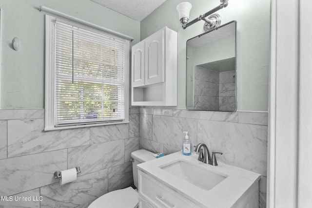 bathroom featuring tile walls, vanity, a textured ceiling, and toilet