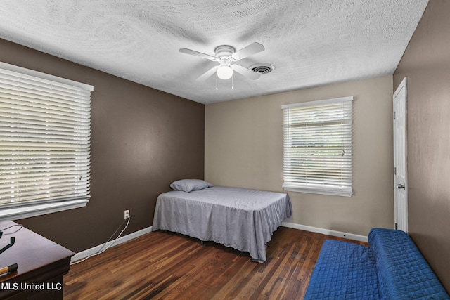 bedroom featuring ceiling fan, dark hardwood / wood-style flooring, and a textured ceiling