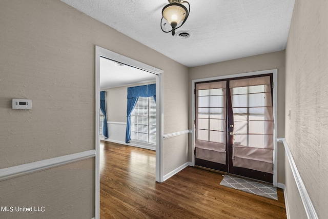 entryway featuring french doors, dark wood-type flooring, and a textured ceiling