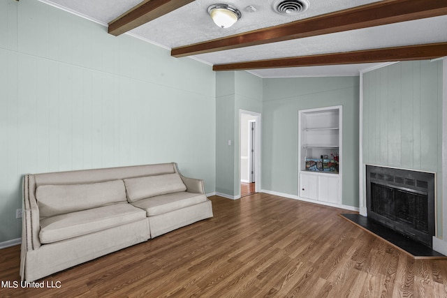 unfurnished living room with wooden walls, hardwood / wood-style flooring, built in shelves, vaulted ceiling with beams, and a large fireplace