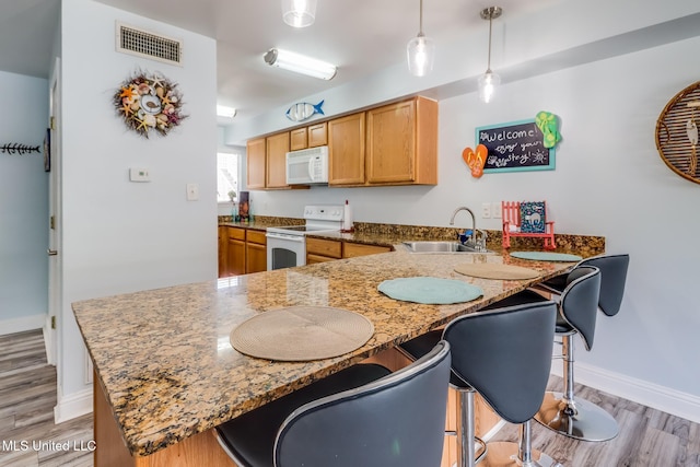 1664 Beach Blvd Unit 172, Biloxi, MS 39531 - kitchen with white appliances, a peninsula, a breakfast bar, light wood-type flooring, and stone counters