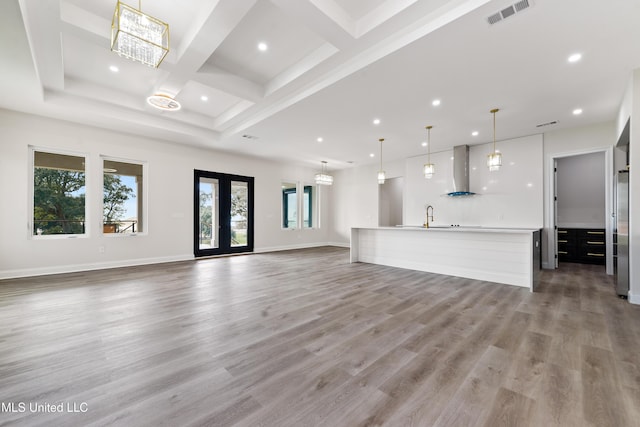 unfurnished living room featuring beam ceiling, light hardwood / wood-style floors, sink, and coffered ceiling