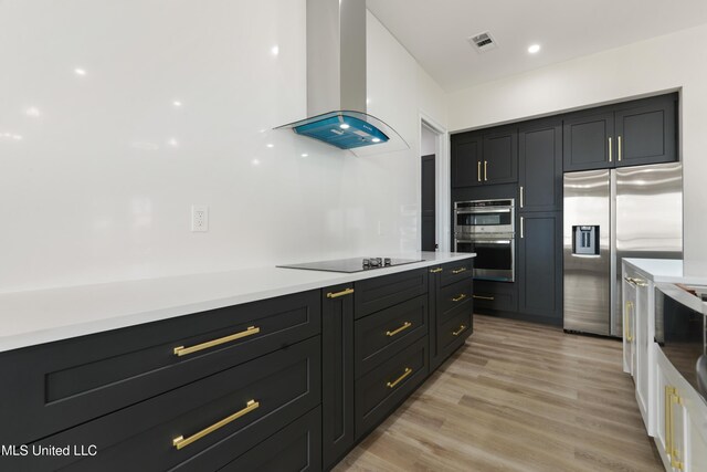 kitchen featuring appliances with stainless steel finishes, light hardwood / wood-style floors, and wall chimney range hood