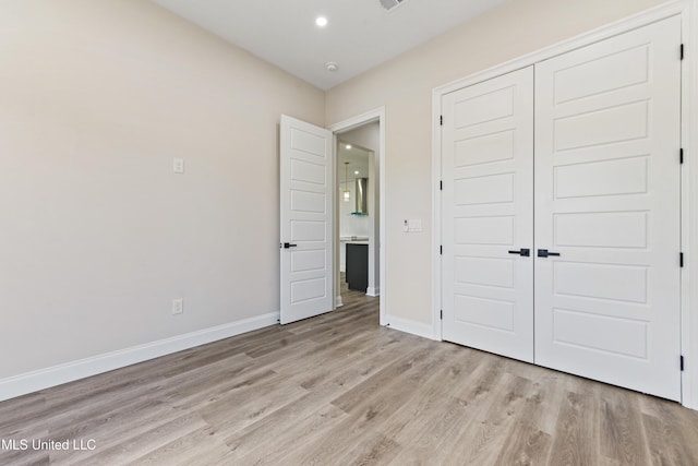 unfurnished bedroom featuring light wood-type flooring and a closet