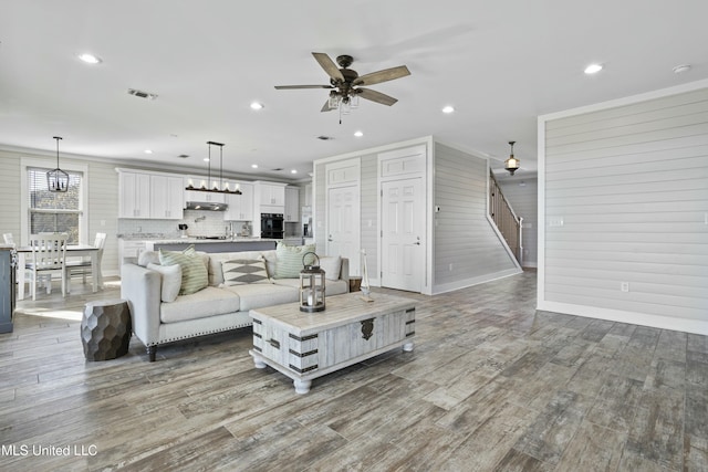 living area featuring visible vents, recessed lighting, stairway, and wood finished floors