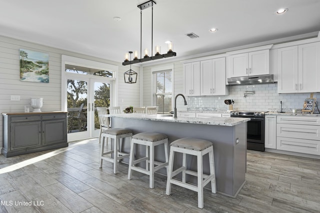 kitchen with visible vents, electric range, a sink, under cabinet range hood, and tasteful backsplash