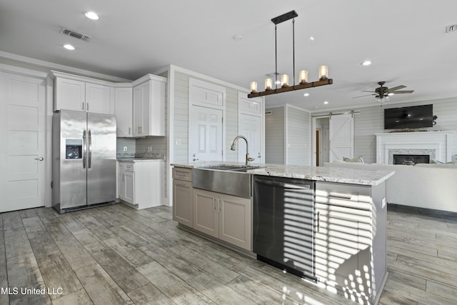 kitchen with visible vents, stainless steel refrigerator with ice dispenser, a barn door, light wood finished floors, and dishwasher