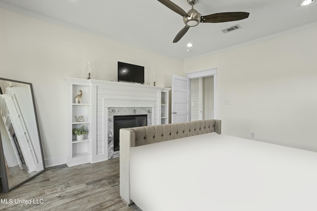 bedroom featuring visible vents, ornamental molding, wood finished floors, a high end fireplace, and recessed lighting