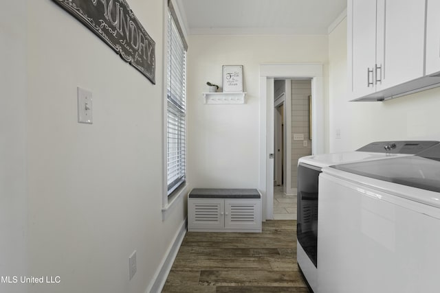 washroom featuring crown molding, baseboards, washer and dryer, dark wood-style floors, and cabinet space