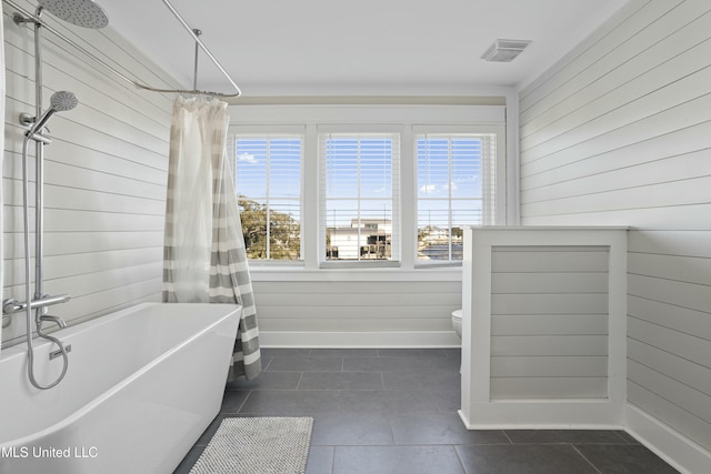 bathroom with visible vents, baseboards, tile patterned flooring, wood walls, and toilet