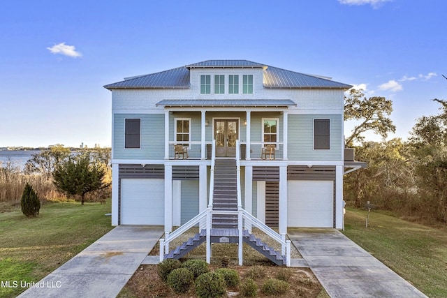 raised beach house with stairway, covered porch, concrete driveway, an attached garage, and a front yard