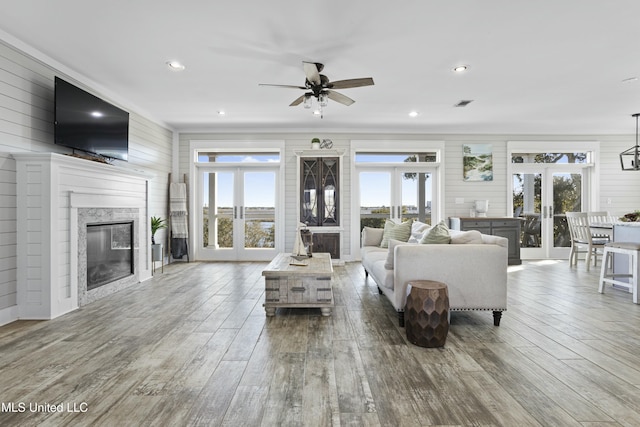 living room featuring a glass covered fireplace, plenty of natural light, french doors, and wood finished floors