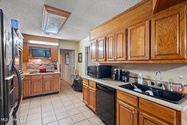 kitchen featuring light tile patterned flooring, tasteful backsplash, sink, black appliances, and a textured ceiling