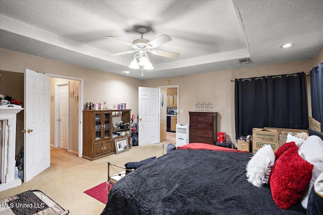 bedroom with ceiling fan, light carpet, a textured ceiling, and a tray ceiling