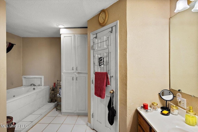 bathroom with tile patterned floors, tiled bath, a textured ceiling, and vanity