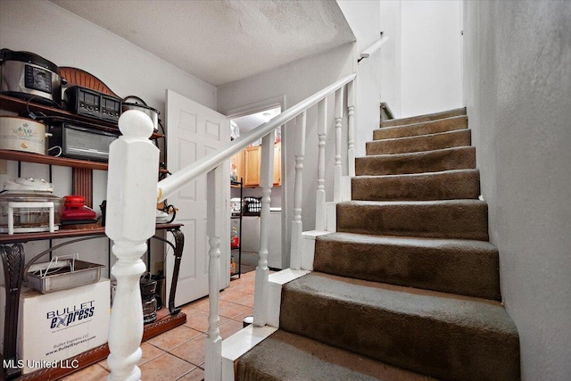 staircase with tile patterned floors and a textured ceiling