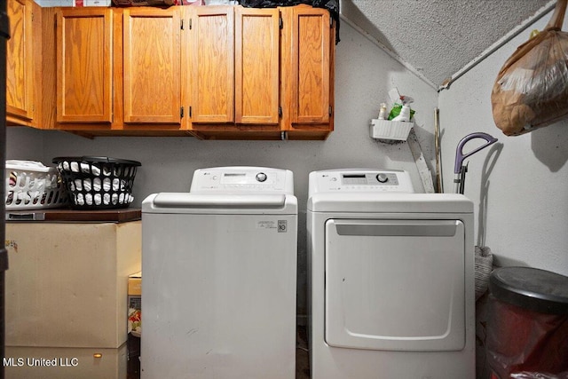 washroom featuring cabinets, washing machine and dryer, and a textured ceiling