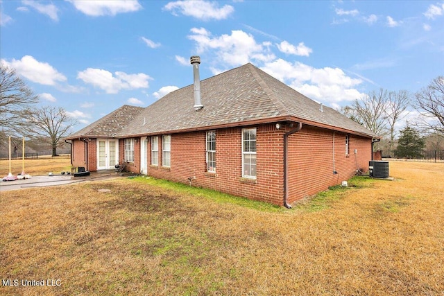 view of side of home with central AC unit and a lawn