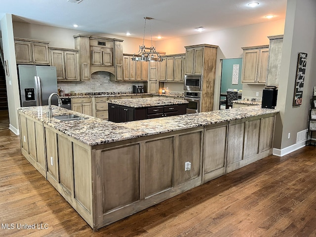 kitchen with sink, appliances with stainless steel finishes, dark hardwood / wood-style floors, and an island with sink