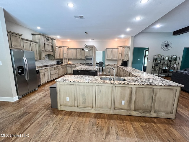 kitchen featuring appliances with stainless steel finishes, dark hardwood / wood-style floors, light stone countertops, and a large island with sink