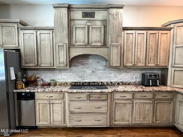 kitchen with dark hardwood / wood-style flooring, light stone counters, black cooktop, stainless steel refrigerator, and tasteful backsplash