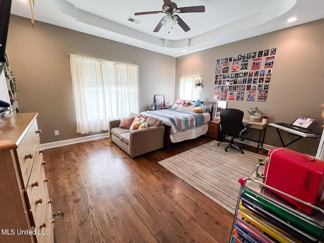 bedroom featuring ceiling fan, a tray ceiling, and dark hardwood / wood-style flooring