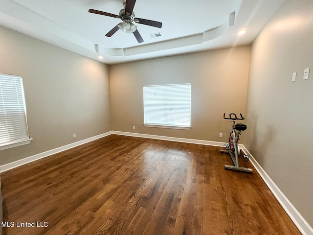 empty room featuring dark hardwood / wood-style floors, a tray ceiling, and ceiling fan