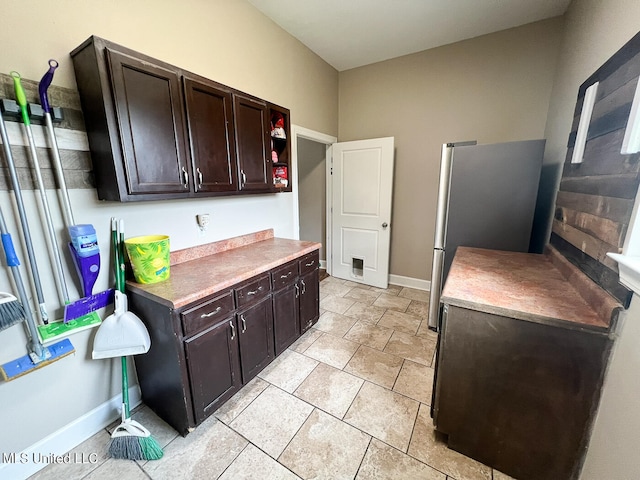 kitchen featuring stainless steel fridge and dark brown cabinetry