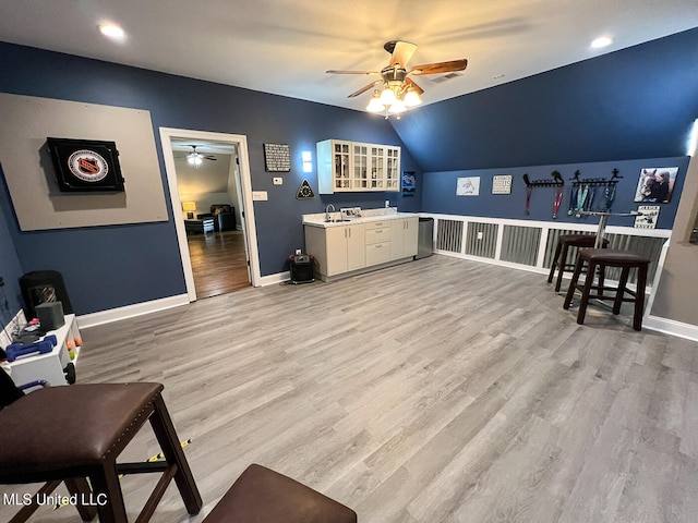 living room with light hardwood / wood-style flooring, ceiling fan, sink, and vaulted ceiling