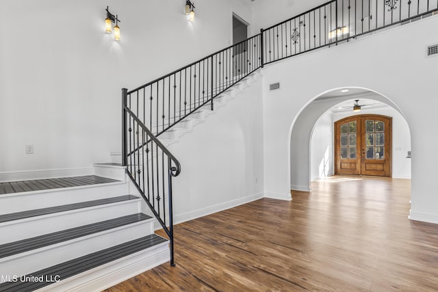 10186 Wire Rd, Vancleave, MS 39565 - stairway with arched walkways, wood finished floors, a towering ceiling, baseboards, and ceiling fan