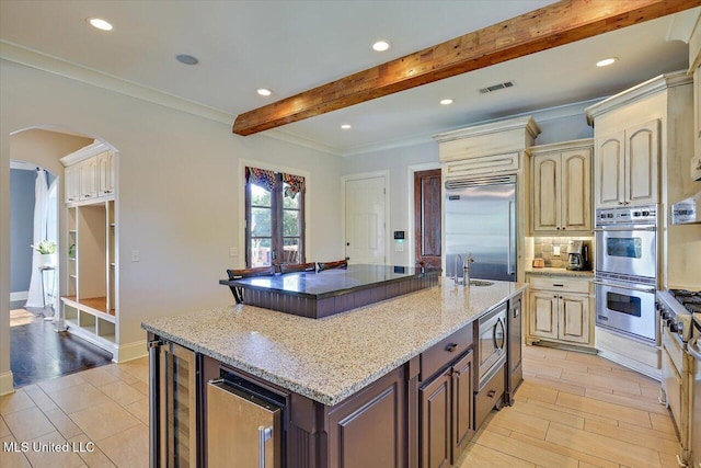 105 Victoria Pl, Madison, MS 39110 - kitchen featuring built in appliances, wine cooler, beamed ceiling, arched walkways, and cream cabinets