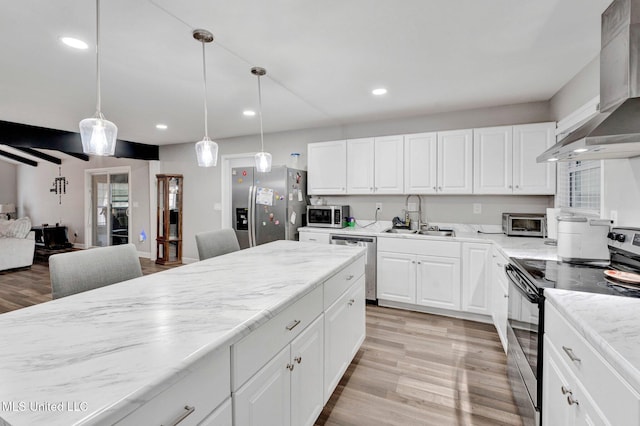 kitchen with wall chimney range hood, sink, stainless steel appliances, white cabinets, and decorative light fixtures