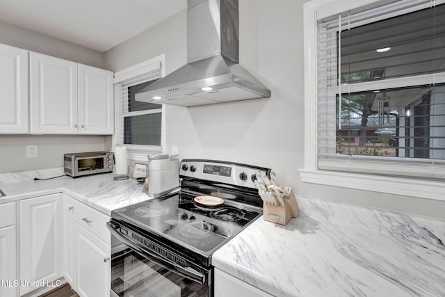 kitchen featuring white cabinets, light stone countertops, electric range, and range hood