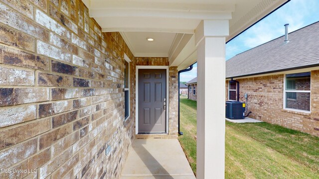 7908 Gardendale Dr, Olive Branch, MS 38654 - view of exterior entry with a lawn, cooling unit, brick siding, and a shingled roof