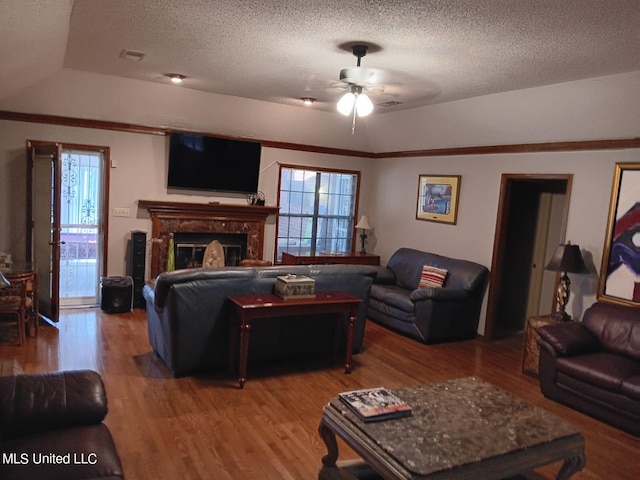 living room featuring ornamental molding, a textured ceiling, hardwood / wood-style flooring, and ceiling fan