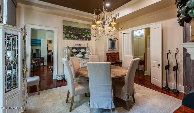 dining space with hardwood / wood-style flooring, crown molding, and a notable chandelier