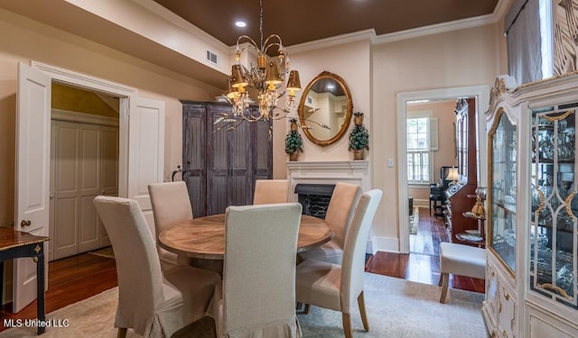 dining room with a chandelier, light hardwood / wood-style floors, and crown molding