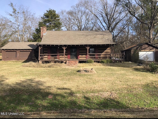 view of front of property featuring a chimney, a detached garage, a front yard, a shingled roof, and a porch