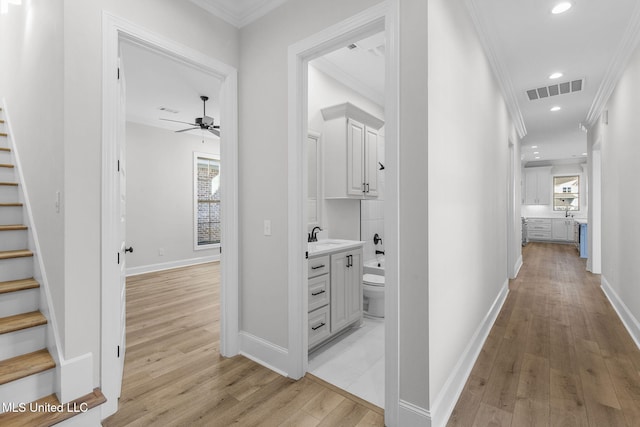 corridor featuring ornamental molding, sink, and light wood-type flooring