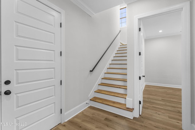 stairway featuring wood-type flooring and ornamental molding