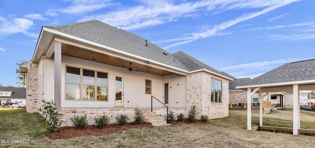 rear view of house with ceiling fan and a lawn