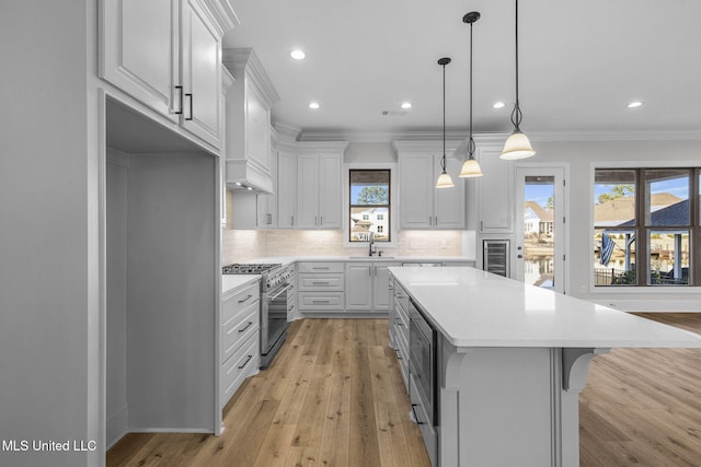 kitchen with high end stainless steel range, a breakfast bar area, white cabinetry, decorative light fixtures, and a center island