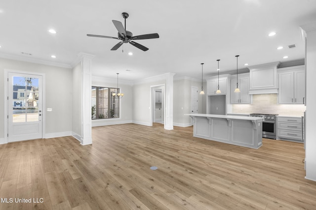 kitchen featuring custom range hood, white cabinets, high end range, and decorative light fixtures