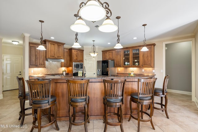 kitchen with stainless steel appliances, brown cabinets, crown molding, and under cabinet range hood