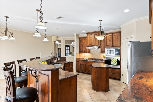 kitchen featuring a kitchen island with sink, under cabinet range hood, a sink, visible vents, and appliances with stainless steel finishes